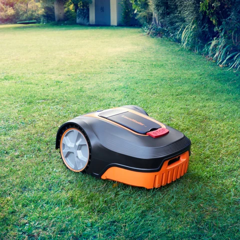 A robot lawn mower, likely the Mammotion YUKA mini 2, operates on a sunny lawn.