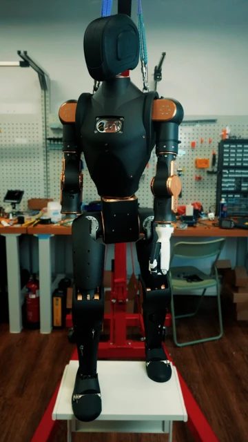 The nearly-assembled Asimov humanoid robot hanging in a workshop.